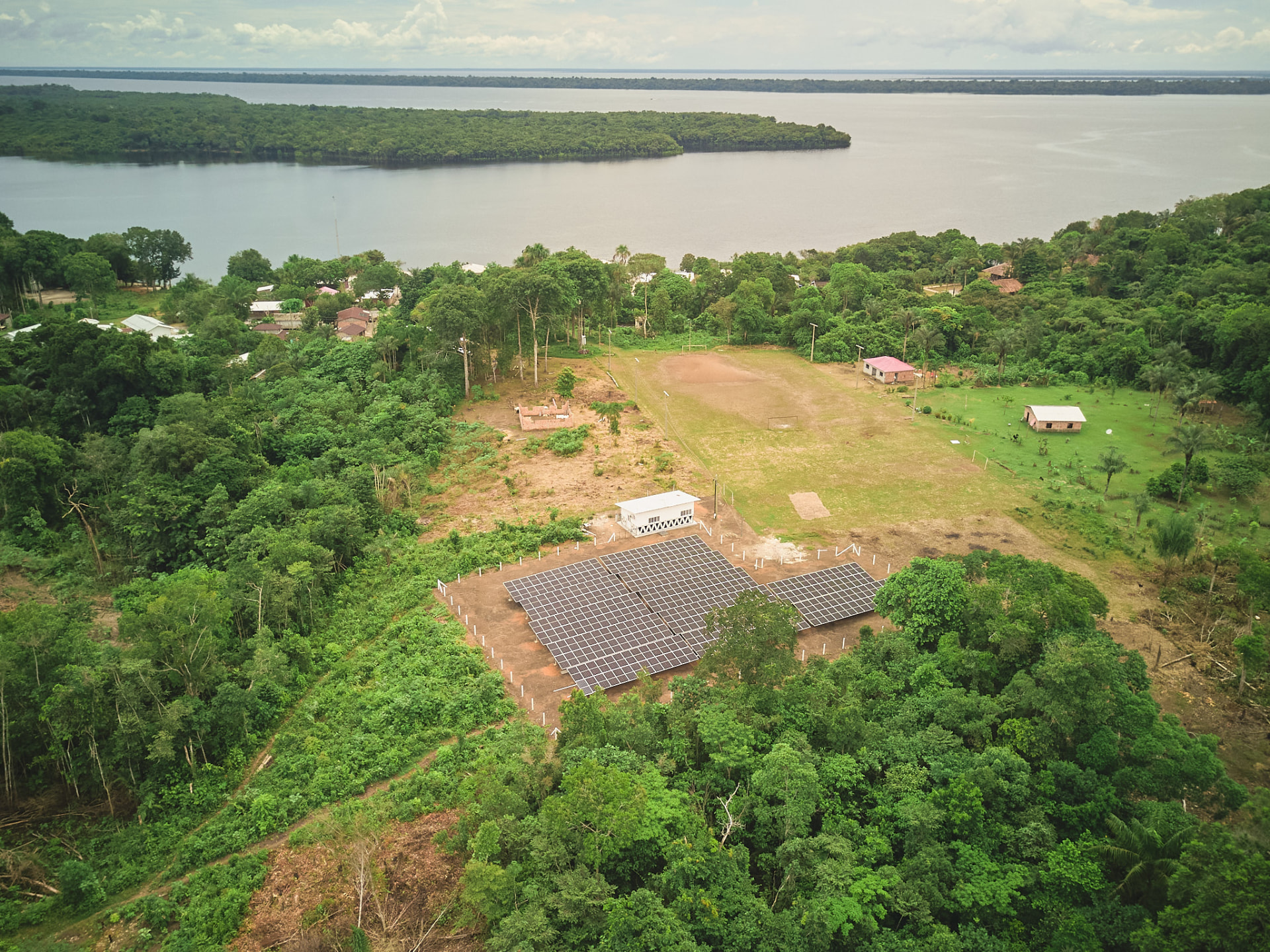 Vista aérea da usina solar da comunidade Três Unidos, cercada pela floresta amazônica e pelo rio