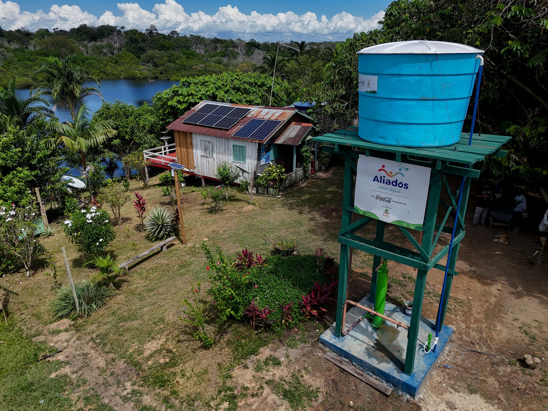 Sistema comunitário de abastecimento de água com caixa d'água elevada e painéis solares em comunidade ribeirinha