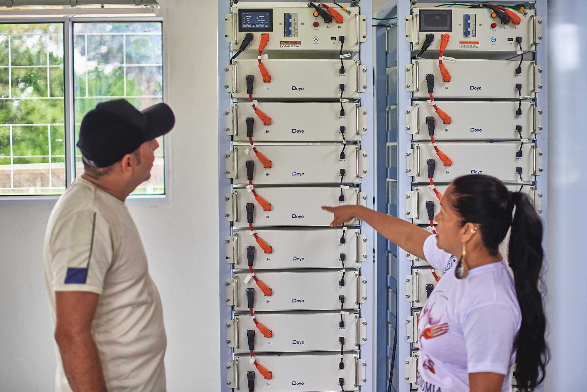 Moradores observam o banco de baterias de um sistema de energia solar comunitário